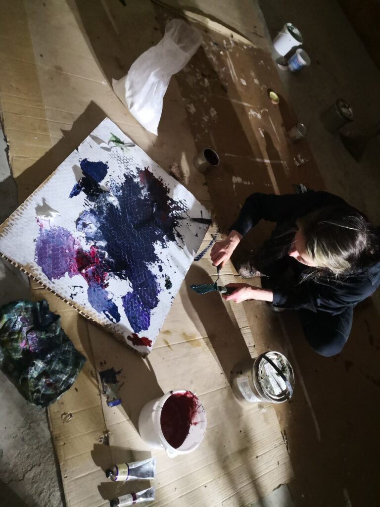 Eine Frau in der Hocke beim Anmischen von Farbe.